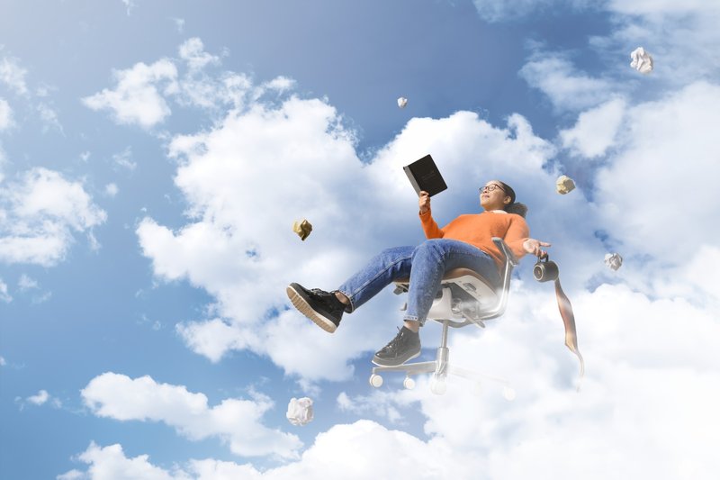 Person floating on an office chair in the sky