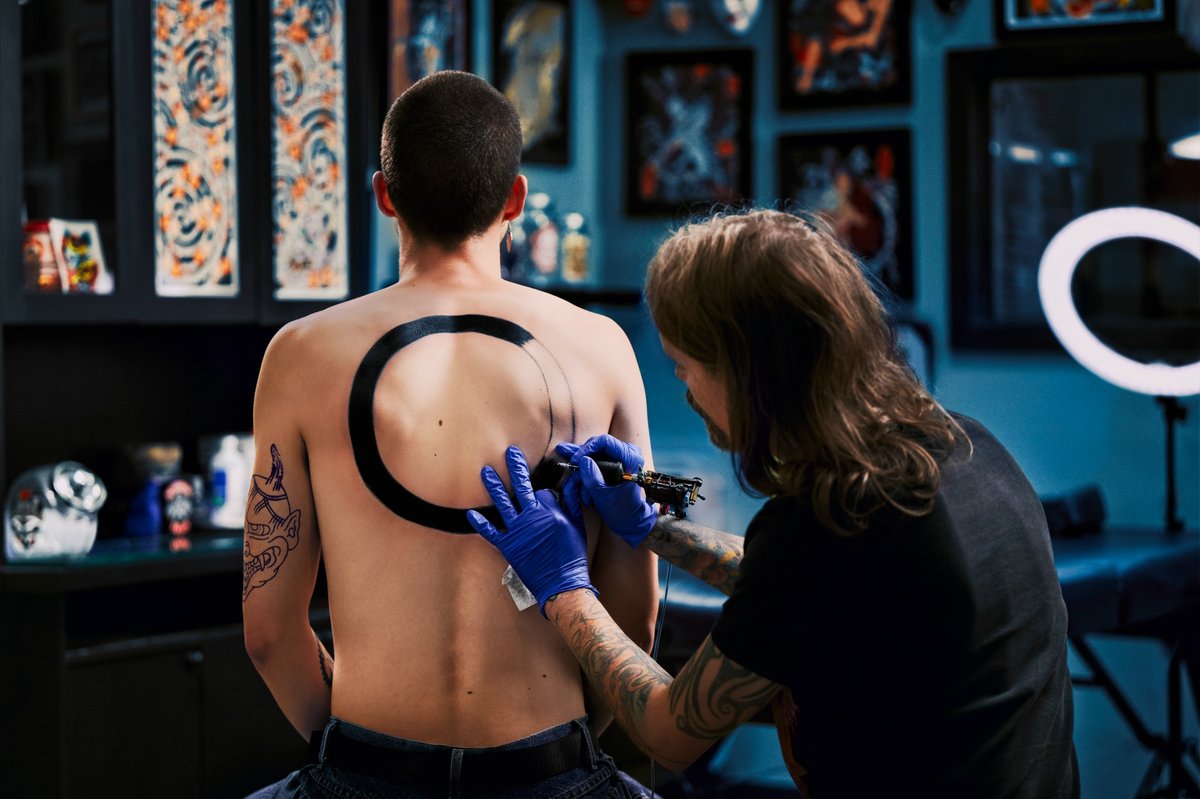 Tattoo artist working on a back tattoo